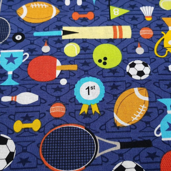 Tela Algodón Día de Deportes - Tela de algodón con dibujos de temática deportiva donde aparecen pelotas de fútbol, pelotas de rugby, tennis, raquetas… sobre un fondo donde predomina el color azul oscuro. Tela del fabricante Fabric Palette. La