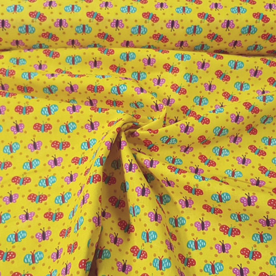 Cotton Butterflies Mustard Colors fabric - Cotton fabric with drawings of colored butterflies on a mustard yellow background. This fabric is part of The Craft Cotton Company's Happy Owls collection. The fabric is 110cm wide and its composition is 100%