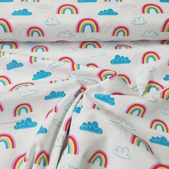 Tela Algodón Arcoiris Nubes - Tela de algodón ancho americano con dibujos de arcoiris y nubes en tonos azules sobre un fondo blanco. La tela mide 110cm de ancho y su composición 100% algodón.