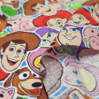 Tela Algodón Disney Toy Story Mosaico - Tela de algodón licencia Disney con dibujos de los personajes de la película Toy Story formando un mosaico. La tela mide 110cm de ancho y su composición 100% algodón.