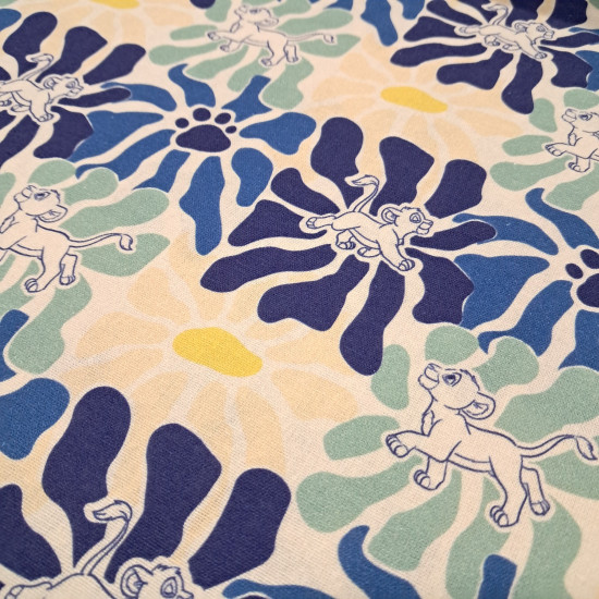 Cream cotton poplin fabric with a graphic pattern of large flowers in blue, mint green, and footprints with the silhouette of Simba from The Lion King.