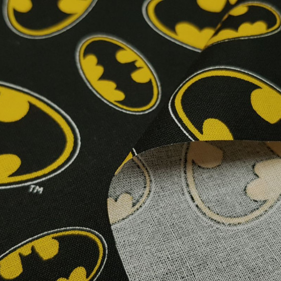 Cotton Batman Logo fabric - Cotton fabric with the legendary logo of the Batman superhero, on a black background. The logo appears in various sizes and positions. The fabric is 110cm wide and its composition 100% cotton.