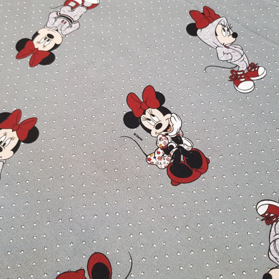 Tela Algodón Disney Minnie Lacitos Topos - Tela de algodón popelín licencia Disney con los dibujos de la ratita Minnie con sudadera deportiva y vestido de flores sobre un fondo gris con topitos. La tela mide 140cm de ancho y su composición 100% algodón.