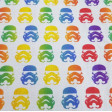 Tela Algodón Star Wars Rainbow Cascos Imperiales - Tela de algodón con dibujos de cascos de los soldados imperiales de la famosa saga Star Wars en estilo “rainbow” multicolor sobre un fondo blanco. La tela mide 150cm de ancho y su composición 100% algodón