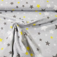 Tela Algodón Estrellas Decorativas Gris - Tela de algodón con dibujos decorativos de estrellas de color blanco, gris oscuro y amarillo sobre un fondo de color gris. La tela mide 160cm de ancho y su composición 100% algodón.