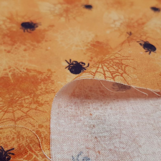 Tela Algodón Halloween Telarañas - Tela de algodón con dibujos de telarañas y arañas de varios tamaños sobre un fondo naranja. La tela mide 150cm de ancho y su composición 100% algodón.