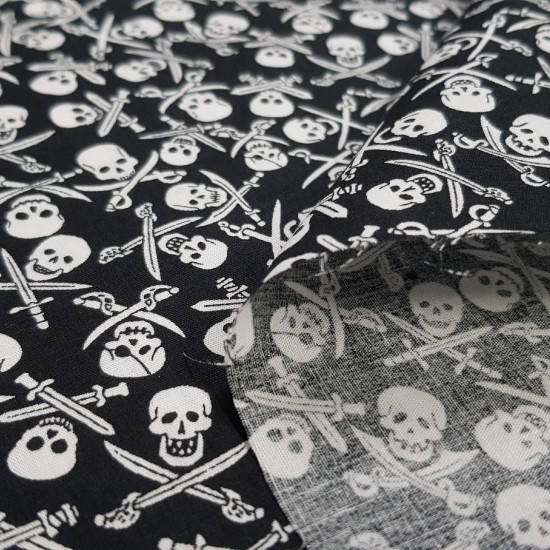 Cotton Skulls Pirate Saber fabric - Cotton fabric with drawings of pirate skulls with crossed sabers on a black background. The fabric is 140cm wide and its composition is 100% cotton.