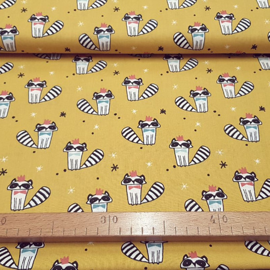 Cotton Raccoons Bow Tie Mustard fabric - Children's cotton poplin fabric with raccoon drawings with bow tie and multi-colored crown on a mustard-colored background with black and white stars. The fabric is 150cm wide and its composition 100% cotton.