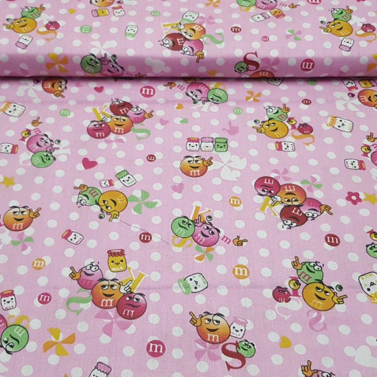 Cotton Balls Chocolate M Pink fabric - Very funny cotton poplin fabric with drawings of the famous colorful M&Ms® chocolate balls on a pink background with white polka dots. The fabric is 150cm wide and its composition 100% cotton.