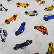 Tela Algodón Coches Colores - Tela de algodón con dibujos de coches de varios colores sobre un fondo blanco. La tela mide 150cm de ancho y su composición 100% algodón.