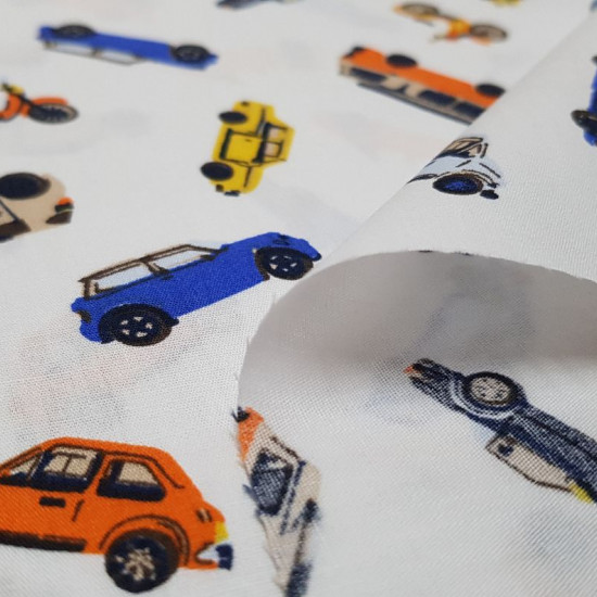 Tela Algodón Coches Colores - Tela de algodón con dibujos de coches de varios colores sobre un fondo blanco. La tela mide 150cm de ancho y su composición 100% algodón.