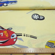 Tela Algodón Coches Carreras - Tela de algodón decorativa con dibujos de coches grandes de carreras sobre un fondo amarillo claro. La tela mide 160cm de ancho y su composición 100% algodón.