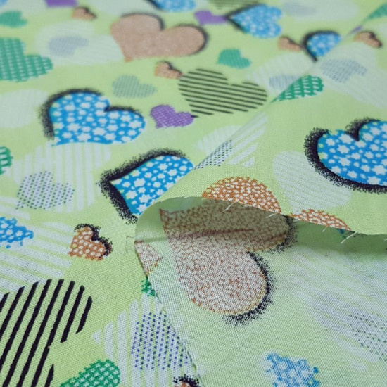 Cotton Hearts Green Background fabric - Cotton fabric with drawings of hearts filled with different shapes on a green background. The fabric is 140cm wide and its composition is 100% cotton.