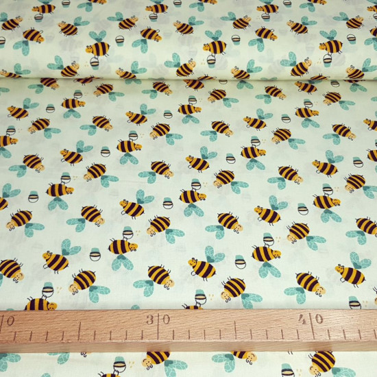Cotton Bees Honey fabric - Cotton poplin fabric with drawings of bees with honey cubes on a light yellow background. The fabric is 150cm wide and its composition is 100% cotton.