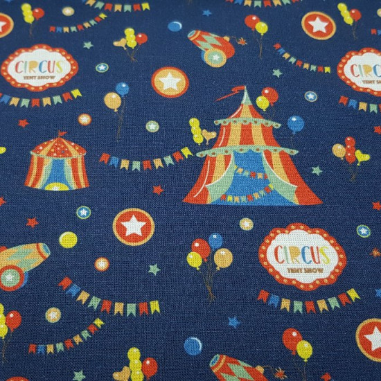 Tela Algodón Circus Carpas - Tela de algodón de temática del circo con dibujos de carpas, globos de colores, cañones, banderines... sobre un fondo azul oscuro. La tela mide 150cm de ancho y su composición 100% algodón.