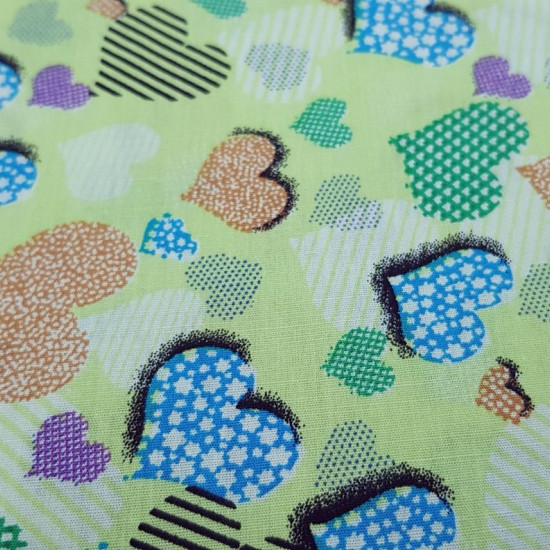 Cotton Hearts Green Background fabric - Cotton fabric with drawings of hearts filled with different shapes on a green background. The fabric is 140cm wide and its composition is 100% cotton.