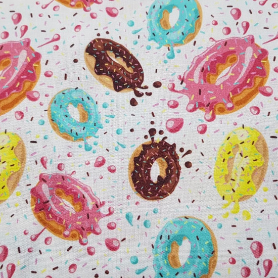 Cotton Donuts Colors fabric - Cotton fabric with drawings of colored glazed donuts on a white background with confetti. The fabric is 150cm wide and its composition is 100% cotton.