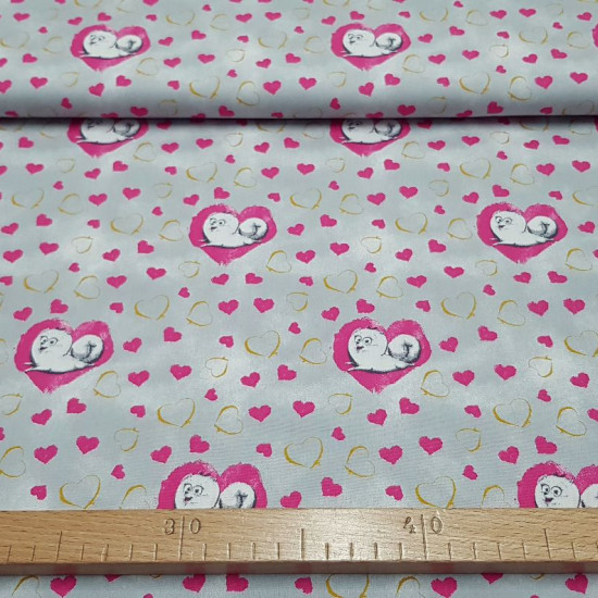 Cotton Pets Bridget Hearts fabric - Cotton fabric licensed Universal Pictures with drawings of the dog Bridget from the movie Pets on a gray background with gold and fuchsia hearts. The fabric is 150cm wide and its composition is 100% cotton.