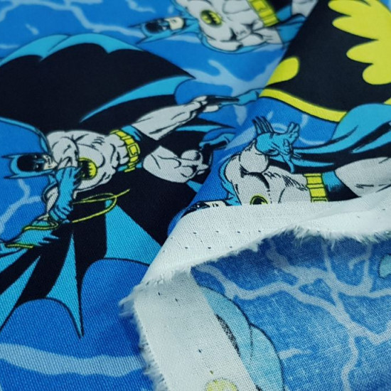 Tela Algodón Batman Azul - Tela de algodón ancho americano con dibujos del superhéroe Batman en varias poses y logotipos de Batman sobre un fondo donde predomina el color azul. La tela mide 110cm de ancho y su composición 100% algodón.