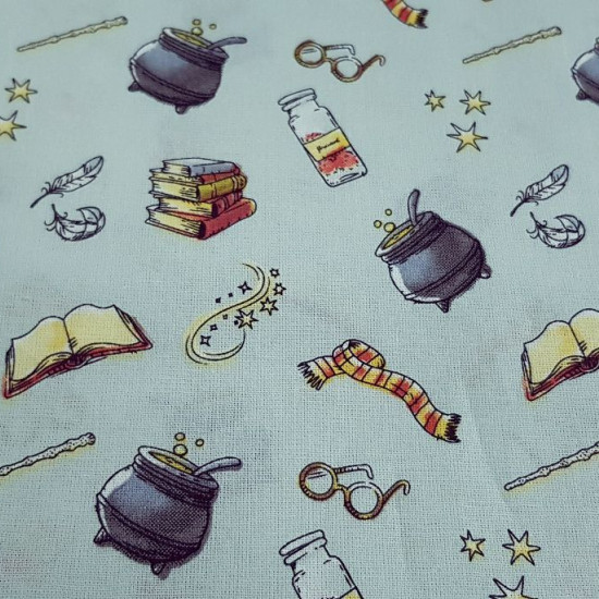 Cotton Harry Potter Objects Cauldrons fabric - Cotton fabric with drawings of objects from the famous Harry Potter saga, where scarves, glasses, cauldrons, magic books... appear on a light blue background. The fabric is 110cm wide and its composition is 1