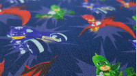 Tela Algodón PJ Masks Vehículos - Tela de popelín algodón licencia con dibujos de los personajes PJ Masks con sus vehículos sobre un fondo azul oscuro. La tela mide 140cm de ancho y su composición 100% algodón.