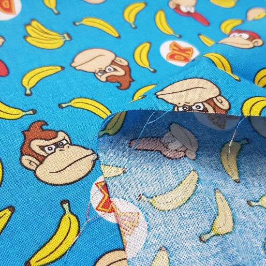 Cotton Donkey Kong Bananas fabric - Licensed cotton fabric with drawings of the characters from the classic video game Donkey Kong on a blue background with bananas. The fabric is 110cm wide and its composition is 100% cotton.