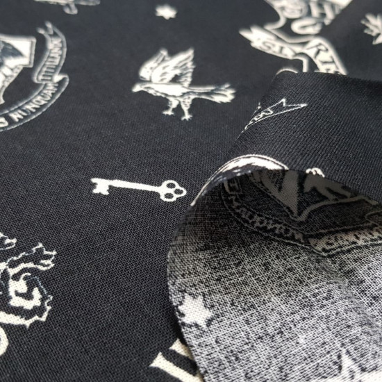 Cotton Harry Potter Hogwarts Badges fabric - License cotton fabric with drawings of Hogwarts badges and other Harry Potter objects, on a black background. The fabric is 110cm wide and its composition is 100% cotton.