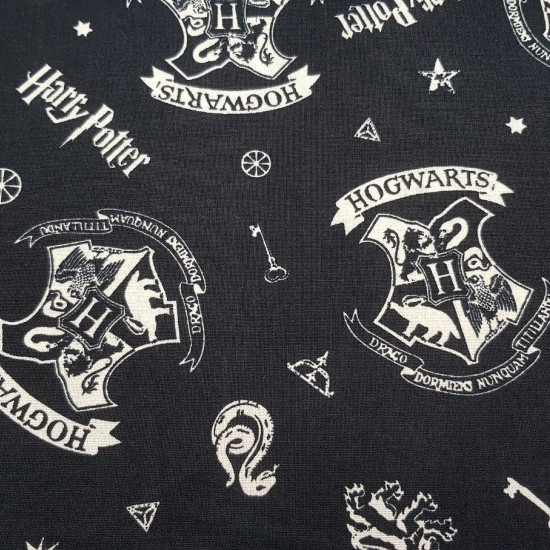 Cotton Harry Potter Hogwarts Badges fabric - License cotton fabric with drawings of Hogwarts badges and other Harry Potter objects, on a black background. The fabric is 110cm wide and its composition is 100% cotton.