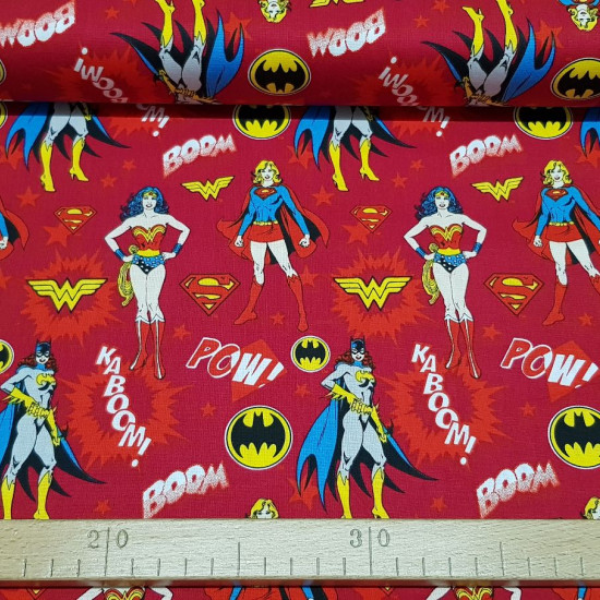 Tela Algodón Heroinas DC Cómic Rojo - Tela de algodón licencia ancho americano con dibujos de las superheroinas de DC Comics (Wonder Woman, Catgirl y Supergirl) sobre un fondo en tono rojo oscuro con onomatopeyas y estrellas. La tela mide 110