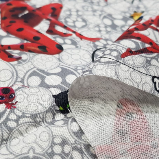 Tela Algodón Ladybug Cat Noir - Tela de algodón licencia con dibujos de los personajes Ladybug y Cat Noir junto a sus kwamis Tikki y Plagg sobre un fondo gris y blanco. La tela mide 140cm de ancho y su composición 100% algodón.