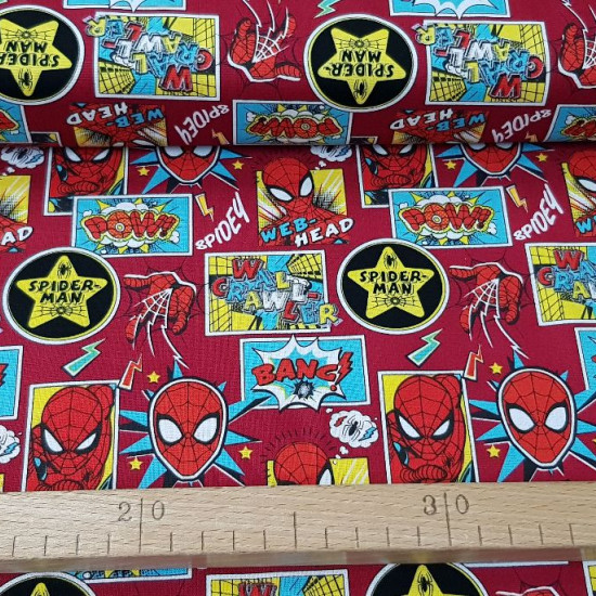 Tela Algodón Spiderman Collage - Tela de algodón ancho americano con dibujos de caras del personaje Spiderman, telarañas, rayos y parches sobre un fondo de color rojo oscuro. La tela mide 110cm de ancho y su composición 100% alg