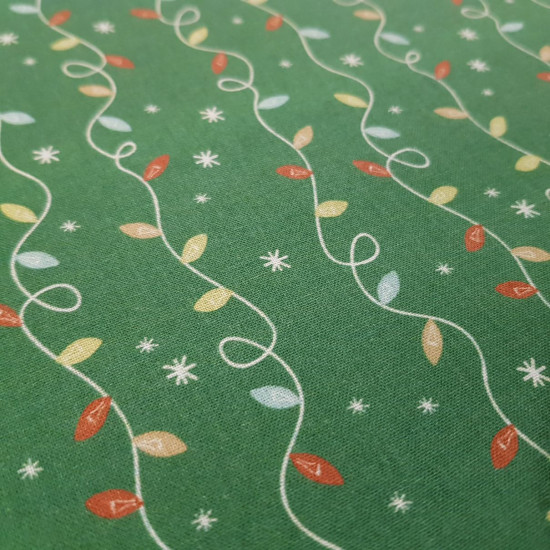 Algodón Navidad Guirnalda Luces - Tela de algodón popelín de temática navideña donde aparecen dibujos de guirnaldas de luces sobre un fondo verde con estrellas blancas. La tela mide 150cm de ancho y su composición 1