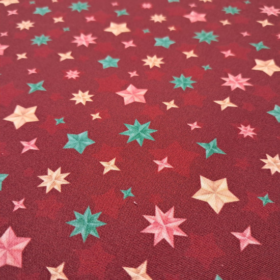Cotton Christmas Stars Wishes fabric - Cotton poplin fabric with Christmas star designs in different shapes and colors on a red/maroon background. The fabric is 150 cm wide and is made of 100% cotton.