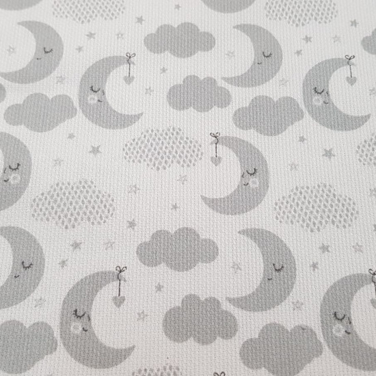 Tela Piqué Lunas Durmiendo - Tela de piqué canutillo infantil con dibujos de lunas durmiendo y nubes grises sobre un fondo blanco. La tela mide 150cm de ancho y su composición 100% algodón.