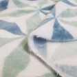 Coral Fleece Triangles Shapes fabric - Very soft and warm coral fleece fabric, with drawings of triangular shapes and forms forming stars in light green and blue colors on a white background. The fabric is 150cm wide and its composition is 100% polyester.