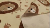 Punto Camiseta Leones - Tela de punto algodón orgánico (GOTS) tipo camiseta con dibujos de leones y huellas sobre un fondo claro. La tela mide 160cm de ancho y su composición 95% algodón – 5% elastano