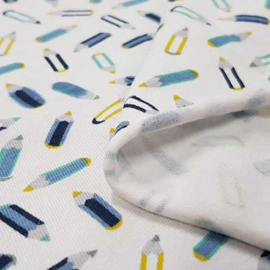 Tela Punto Algodón Lápices - Tela de punto algodón tipo camiseta con dibujos de lápices en tonos azules sobre un fondo blanco. La tela mide 150cm de ancho y su composición 95% algodón - 5% elastano