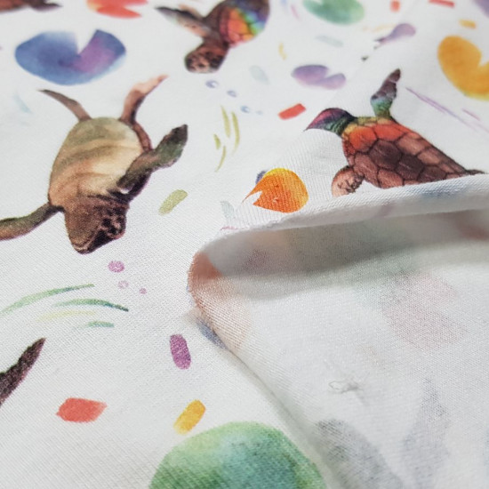 Tela Punto Camiseta Tortugas - Tela de punto algodón tipo camiseta estampación digital con dibujos de tortugas con caparazones de colores y formas de discos de colores sobre un fondo blanco. La tela mide 150cm de ancho y su composición 95% algodón