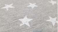 Tela Punto Sudadera Alpenfleece Estrellas - Tela de punto sudadera con pelo por uno de los lados y por el otro dibujos de estrellas blancas sobre un fondo gris melange. La tela mide 150cm de ancho y su composición 56% poliester - 40% algodón - 4% elastano