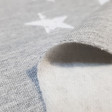 Sweatshirt Alpenfleece Stars fabric - Sweatshirt fabric with fur on one side and drawings of white stars on a melange gray background on the other. The fabric is 150cm wide and its composition is 56% polyester - 40% cotton - 4% elastane.