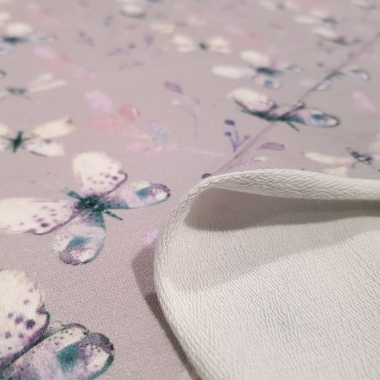 French Terry Sweatshirt Butterflies fabric - French Terry Swatshirt fabric, with gigital printing drawings of butterflies and twigs where the background lilac color predominates. The fabric is 150cm wide and its composition is 95% cotton - 5% elastane.