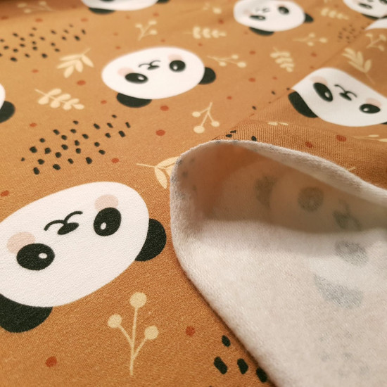 French Terry Sweatshirt Brushed Panda Bears fabric - French terry sweatshirt fabric with brushed inner face, featuring drawings of panda bear faces and twigs on a light rust-colored background. The fabric is 150cm wide and its composition is 95% cotton - 