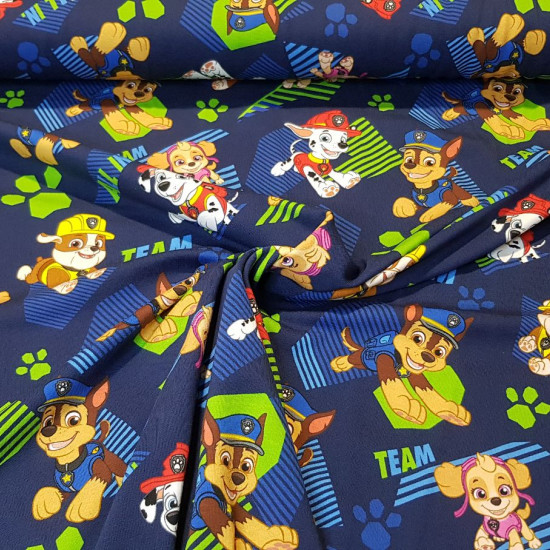 Cotton Jersey Paw Patrol Navy blue fabric - Cotton jersey fabric with drawings of the Paw Patrol characters on a navy blue background with colored footprints. The fabric is 155cm wide and its composition 95% cotton - 5% elastane