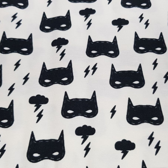 Tela Punto Algodón Antifaz Superhéroe - Tela de punto camiseta con motivos de superhéroes donde aparecen dibujos de máscaras o antifaces negros, nubes y rayos sobre un fondo blanco roto. La tela mide 150cm de ancho y su composición 94% algodón –&
