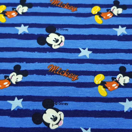 Tela Punto Camiseta Disney Mickey Rayas - Tela elástica de punto algodón licencia Disney con dibujos del personaje Mickey sobre un fondo azul con rayas y estrellas. La tela mide 150cm de ancho y su composición 95% algodón - 5% elastano.