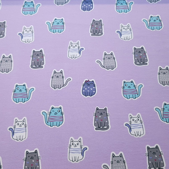 Punto Camiseta Gatitos Lila - Tela de punto algodón tipo camiseta con dibujos de gatos sonrientes sobre un fondo lila. La tela mide 145cm de ancho y su composición 95% algodón - 5% elastano.