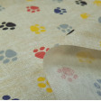 Loneta Huellas Perritos fabric - Tela muy colorida de tejido loneta con dibujos de huellas de perro de varios colores sobre un fondo claro casi blanco. La loneta es perfecta para creaciones y trabajos de decoración, ya que cuenta con un ancho de 280cm q