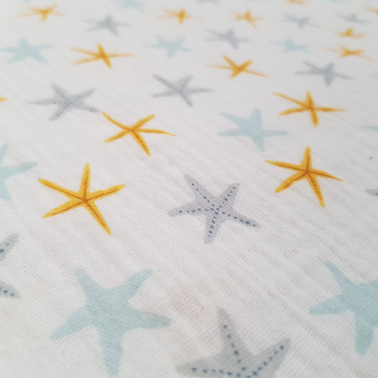 Double Gauze Starfish fabric - Double gauze cotton fabric with colorful starfish drawings on a white background. A fabric with a maritime or summer theme, which reminds us of the smell of the beach. The fabric measures 135cm wide and its compositi